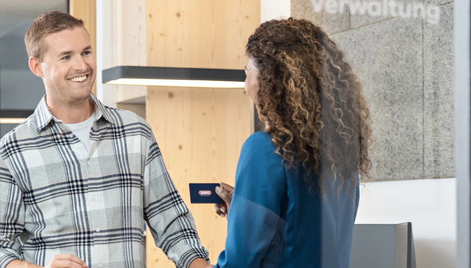 A woman hands over an access medium to a new colleague.