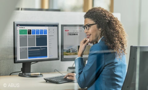 Eine Frau sitzt vor einem Monitor, auf dem der TECTIQ-Schließplan zu sehen ist.