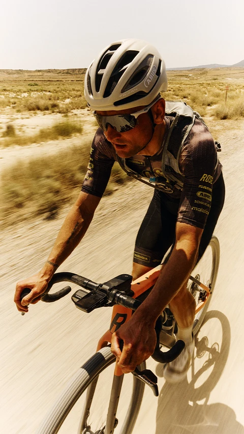 Profi-Radfahrer auf staubiger Naturstrecke in hügeliger Landschaft mit dem Road Fahrradhelm Taipan © ABUS Profi-Radfahrer auf staubiger Naturstrecke in hügeliger Landschaft mit dem Road Fahrradhelm Taipan © ABUS