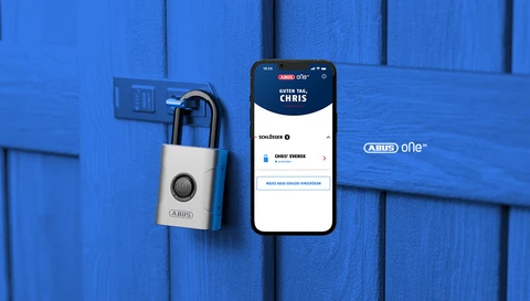 Smartes Vorhängeschloss EVEROX One an einer Schuppentür aus Holz und ein Smartphone mit App-Screen im Vordergrund © ABUS